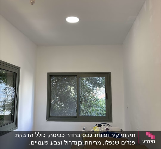 חדר עם קירות צבועים, חלון וכלי עבודה על הרצפה